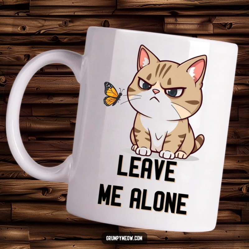 Funny mug featuring a grumpy cat trying to ignore a playful butterfly fluttering nearby, expressing humorous irritation.
