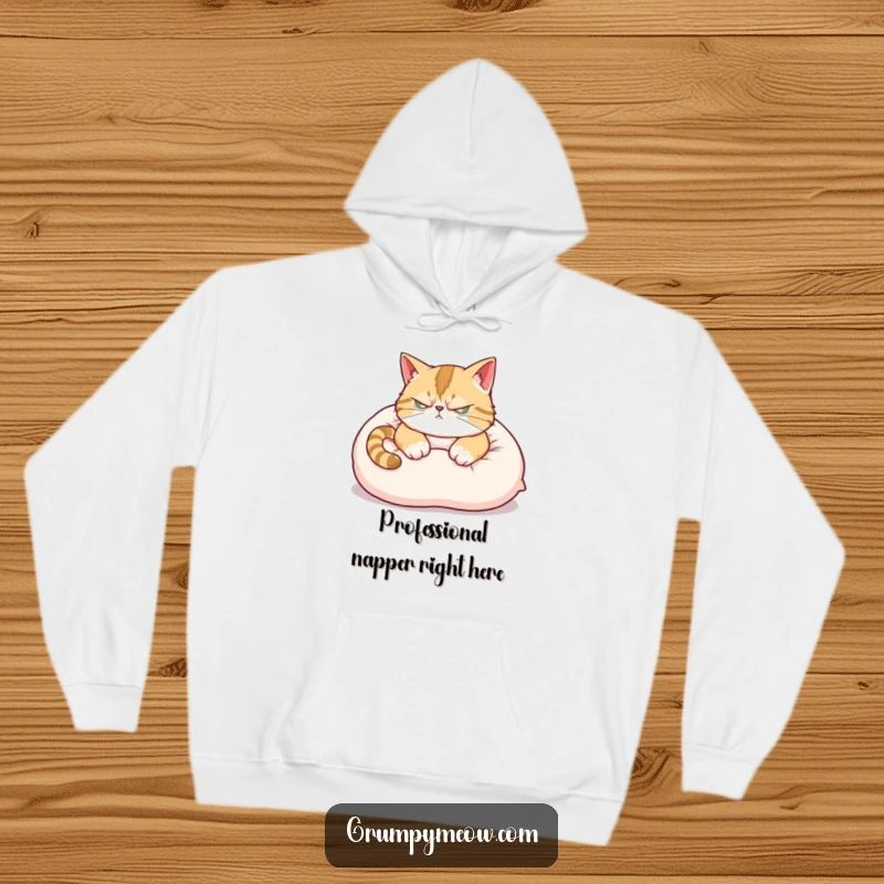 Funny Hoodie: A grumpy cat with a scowling face attempts a nap on a soft pillow, ear twitching, looking annoyed.