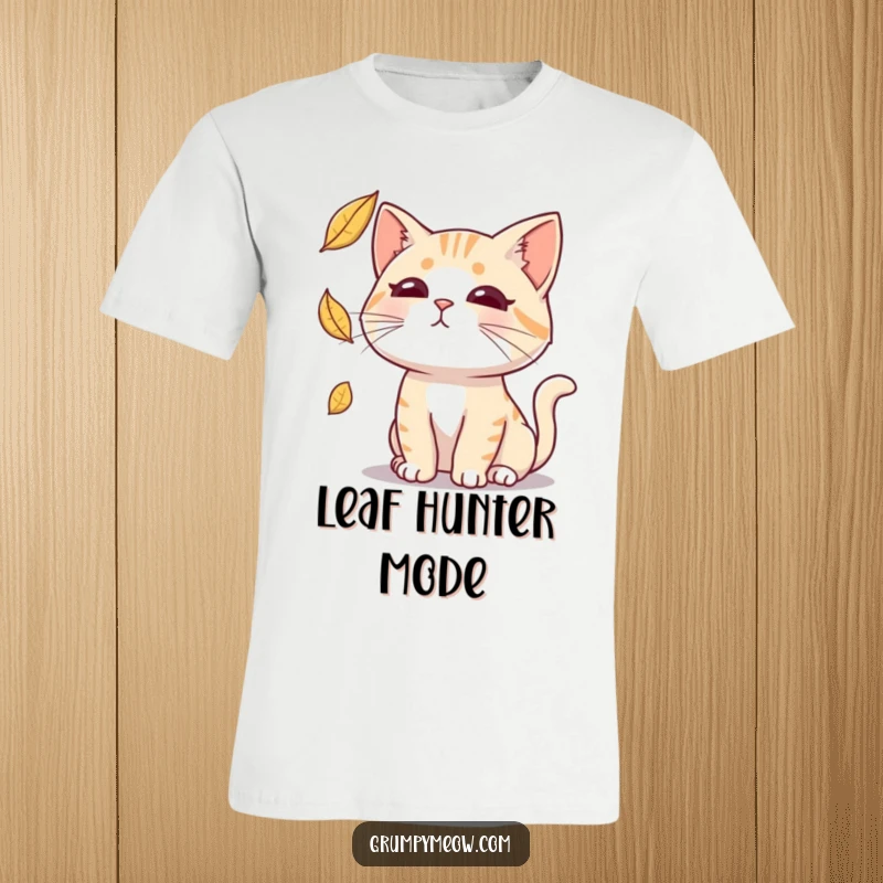 Funny t-shirt of a cat with a blank expression intensely focused on catching a falling leaf, capturing aloof humor.
