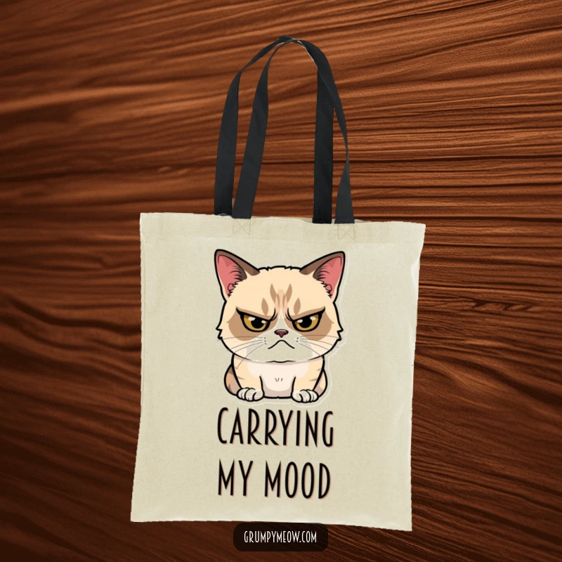 Funny Tote Bag with a grumpy cat glaring intensely, yet sporting a tiny, hidden smile, perfect for carrying essentials with attitude.